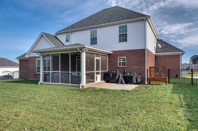 rear view of property with a lawn, a patio area, and a sunroom