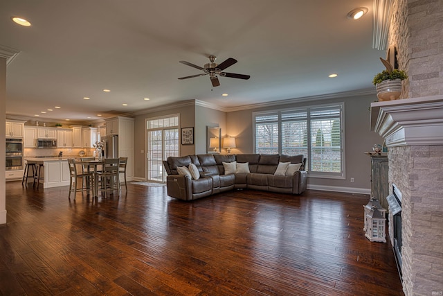 living room with ceiling fan, a large fireplace, a healthy amount of sunlight, and dark hardwood / wood-style floors