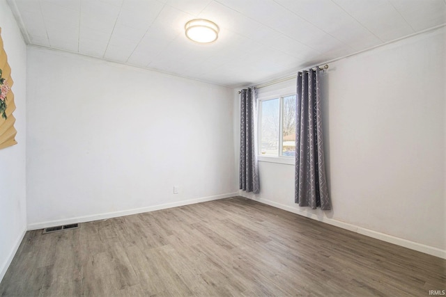 unfurnished room with wood finished floors, visible vents, and baseboards