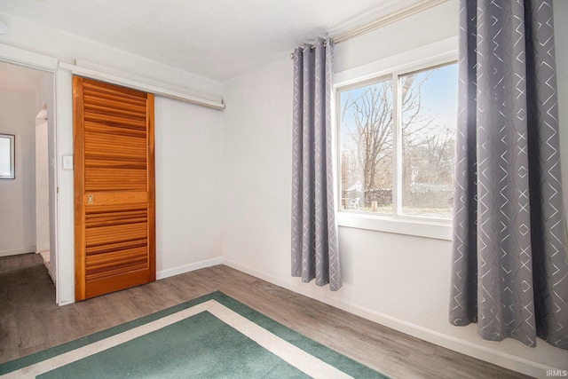 unfurnished bedroom featuring a closet, baseboards, and wood finished floors