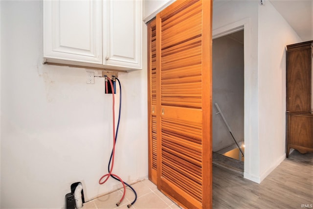 laundry room with hookup for a washing machine, cabinet space, and light wood-style floors