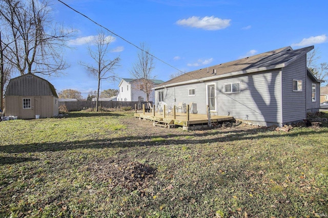 rear view of property with a wooden deck, a yard, and a shed