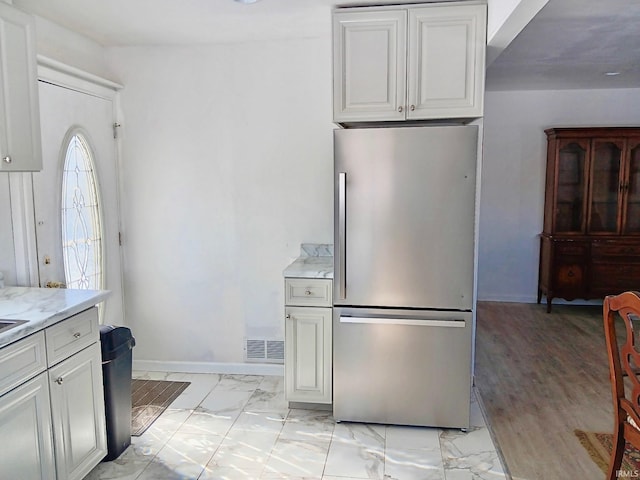 kitchen with baseboards, visible vents, white cabinets, freestanding refrigerator, and marble finish floor