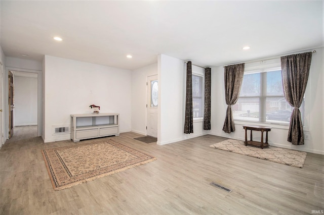 living area featuring light wood-style floors, baseboards, visible vents, and recessed lighting