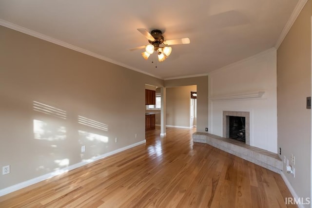 unfurnished living room with ceiling fan, light wood-type flooring, crown molding, and a tile fireplace