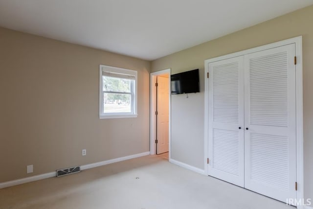 unfurnished bedroom featuring light carpet and a closet