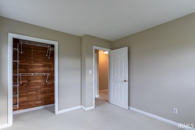 unfurnished bedroom featuring light carpet, a closet, and wood walls