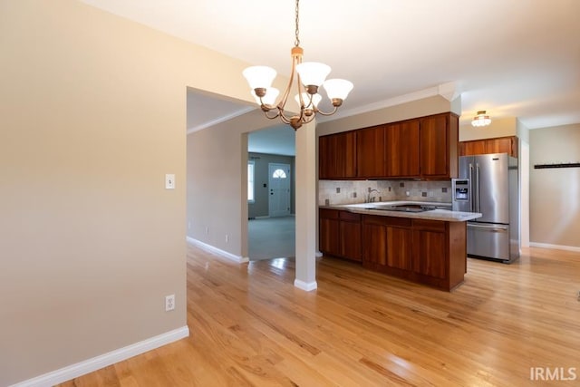 kitchen featuring tasteful backsplash, ornamental molding, a chandelier, stainless steel fridge with ice dispenser, and light hardwood / wood-style floors