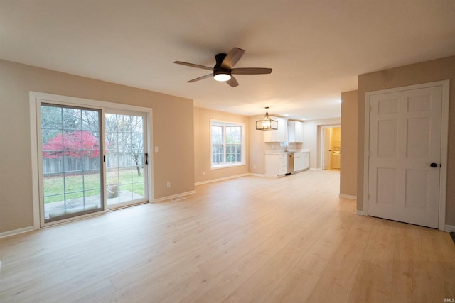 unfurnished living room with ceiling fan with notable chandelier and light wood-type flooring