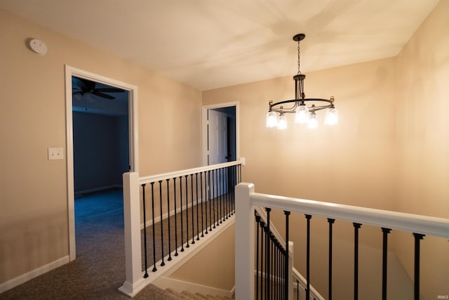 corridor featuring dark carpet and a notable chandelier