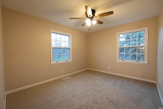 carpeted empty room featuring ceiling fan and a wealth of natural light