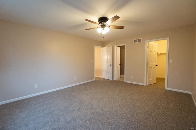 unfurnished bedroom featuring carpet, a spacious closet, a closet, and ceiling fan