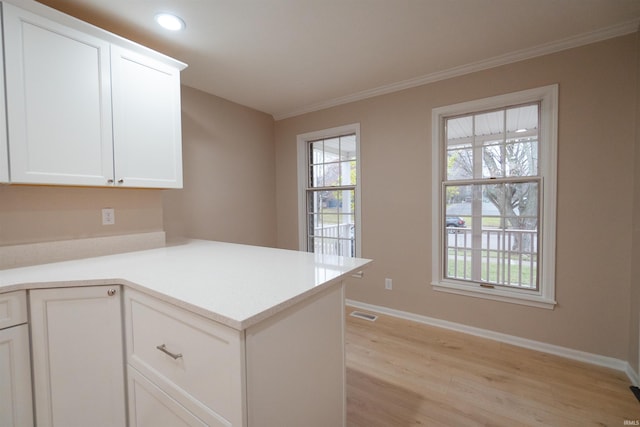 kitchen featuring kitchen peninsula, light hardwood / wood-style flooring, white cabinets, and ornamental molding