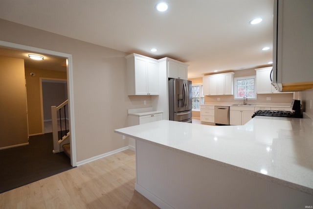 kitchen with white cabinets, sink, kitchen peninsula, and stainless steel appliances