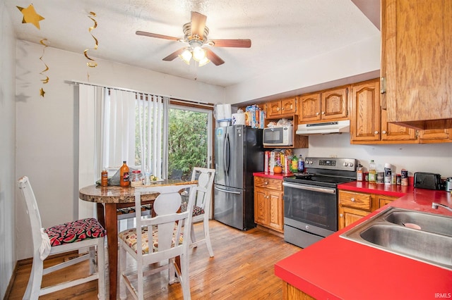 kitchen featuring sink, ceiling fan, stainless steel appliances, a textured ceiling, and light wood-type flooring