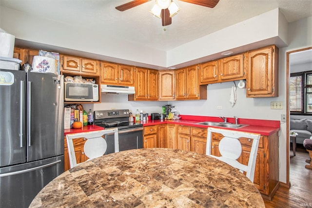 kitchen with sink, dark wood-type flooring, ceiling fan, stainless steel appliances, and a textured ceiling