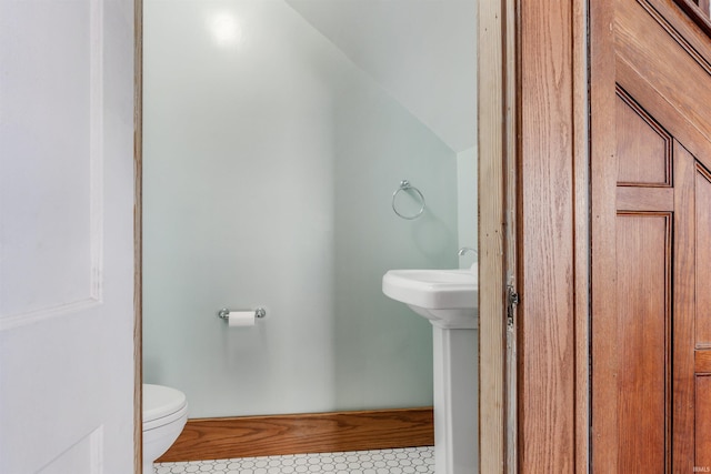 bathroom with tile patterned floors, toilet, and lofted ceiling