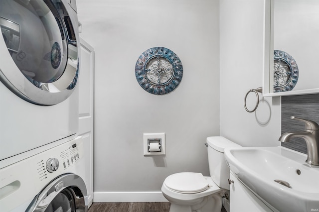 bathroom featuring hardwood / wood-style flooring, stacked washer / drying machine, toilet, and vanity