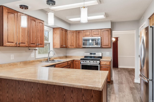 kitchen with decorative light fixtures, sink, kitchen peninsula, and stainless steel appliances