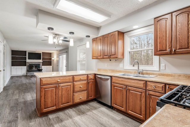 kitchen with ceiling fan, sink, stainless steel appliances, kitchen peninsula, and light hardwood / wood-style floors