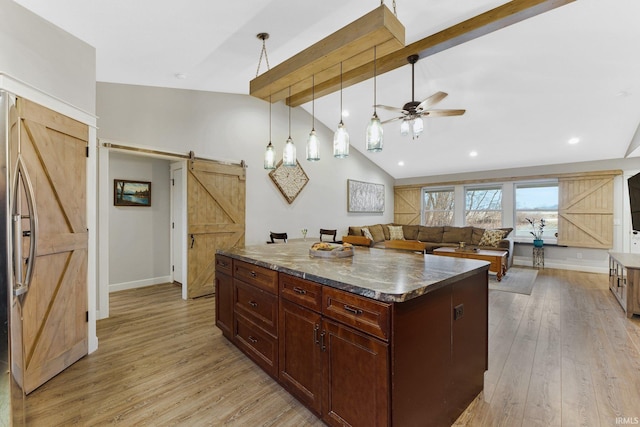 kitchen with stainless steel refrigerator, ceiling fan, a barn door, lofted ceiling with beams, and light hardwood / wood-style floors