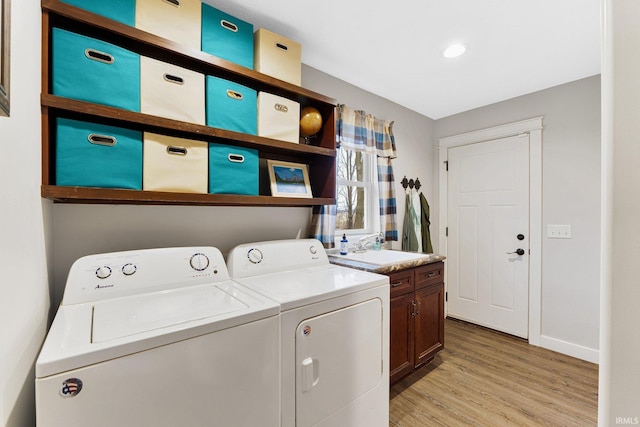 washroom with light hardwood / wood-style floors, sink, cabinets, and independent washer and dryer