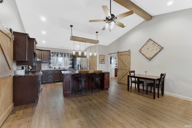 kitchen with stainless steel appliances, a barn door, beamed ceiling, a center island, and dark hardwood / wood-style floors