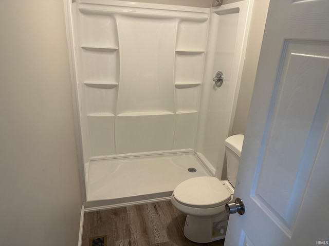 bathroom with toilet, wood-type flooring, and walk in shower