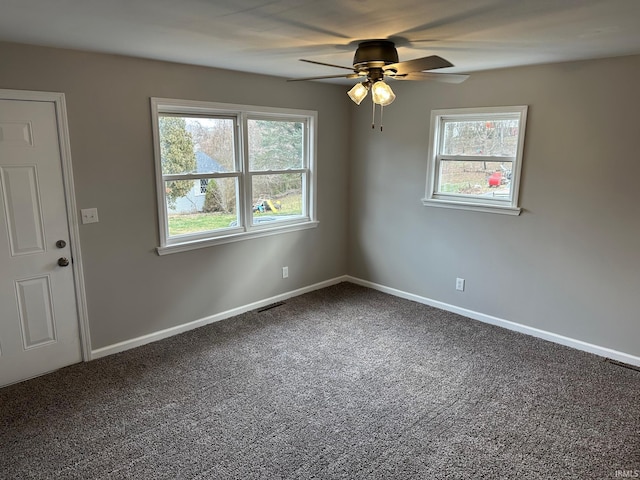 carpeted empty room with ceiling fan and a wealth of natural light