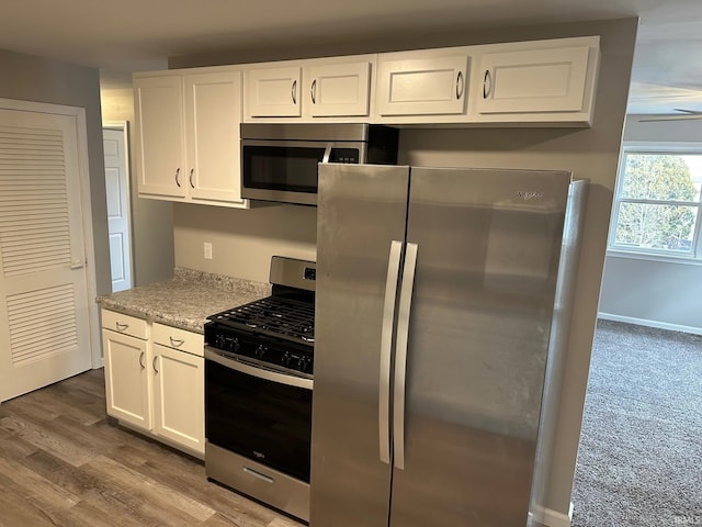 kitchen with white cabinets, wood-type flooring, and appliances with stainless steel finishes