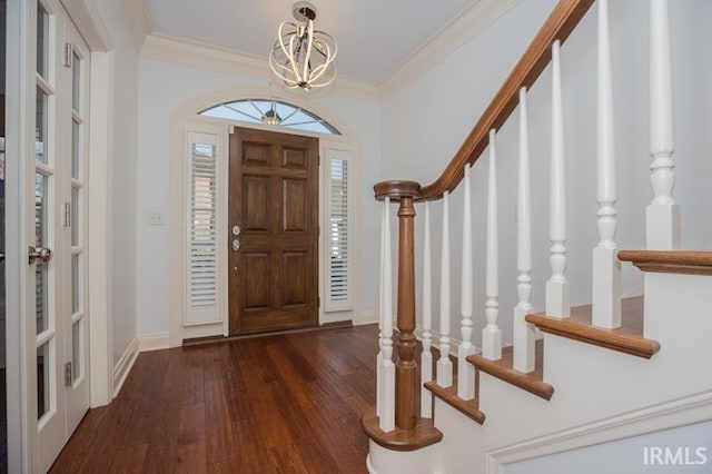 foyer with dark hardwood / wood-style flooring, ornamental molding, and a chandelier