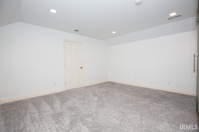 carpeted spare room with lofted ceiling