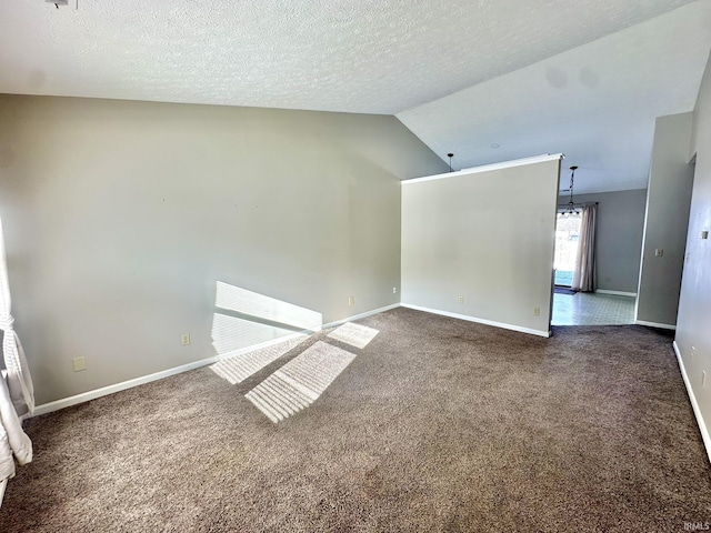 empty room featuring dark colored carpet, a textured ceiling, and lofted ceiling