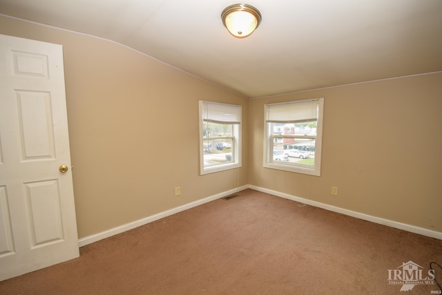 carpeted empty room with vaulted ceiling