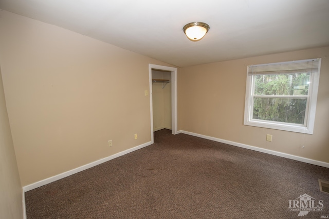 unfurnished room with dark carpet and lofted ceiling