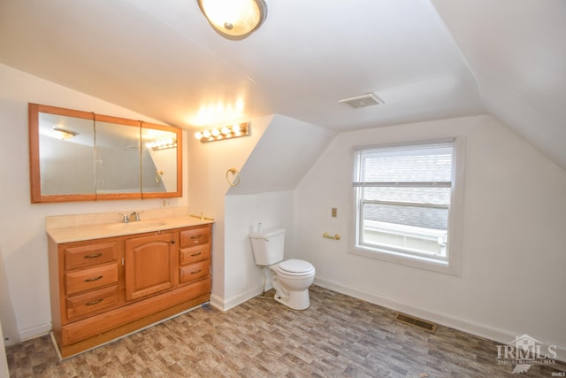 bathroom featuring toilet, vanity, hardwood / wood-style flooring, and vaulted ceiling