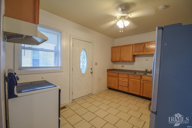 kitchen with extractor fan, ceiling fan, sink, washer / dryer, and stainless steel refrigerator