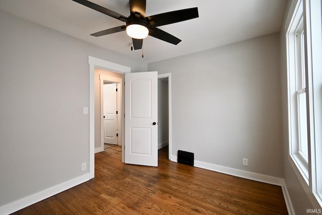 unfurnished bedroom with ceiling fan and dark wood-type flooring