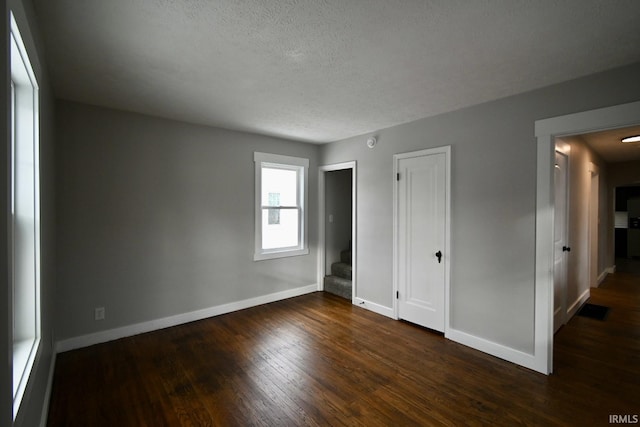 unfurnished bedroom with dark hardwood / wood-style flooring and a textured ceiling