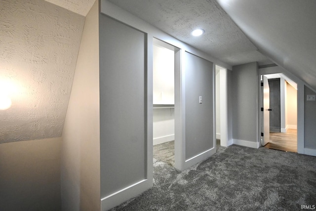 bonus room with a textured ceiling, dark carpet, and vaulted ceiling