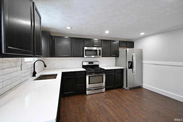 kitchen with appliances with stainless steel finishes, a textured ceiling, dark hardwood / wood-style flooring, and sink