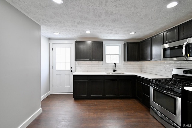 kitchen featuring dark wood-type flooring, sink, appliances with stainless steel finishes, and tasteful backsplash