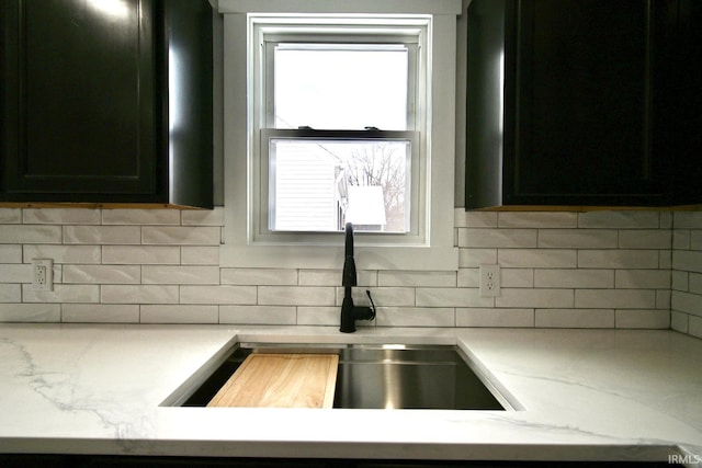 kitchen with tasteful backsplash, light stone counters, and sink