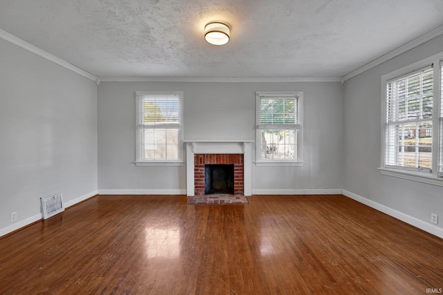 unfurnished living room with a wealth of natural light, hardwood / wood-style floors, ornamental molding, and a brick fireplace