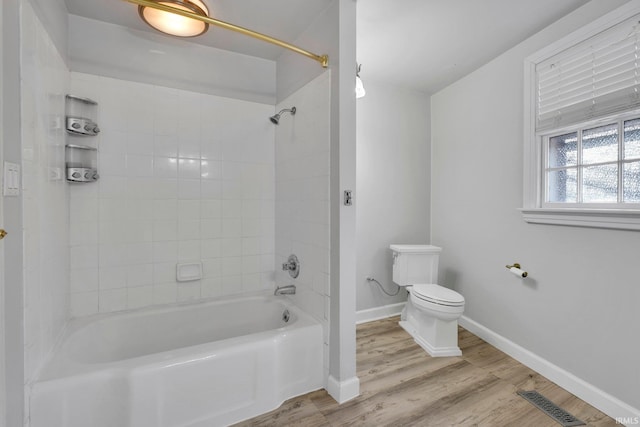 bathroom featuring hardwood / wood-style floors, washtub / shower combination, and toilet