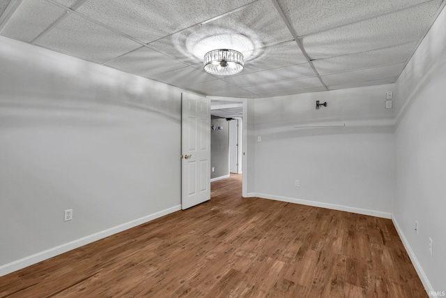 unfurnished room with a paneled ceiling and wood-type flooring