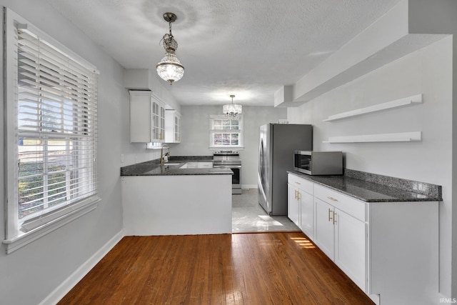 kitchen featuring pendant lighting, stainless steel appliances, white cabinetry, and a notable chandelier