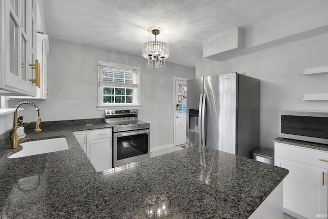 kitchen featuring pendant lighting, sink, a textured ceiling, white cabinetry, and stainless steel appliances