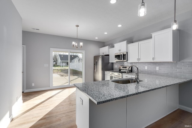 kitchen with white cabinets, pendant lighting, kitchen peninsula, and appliances with stainless steel finishes