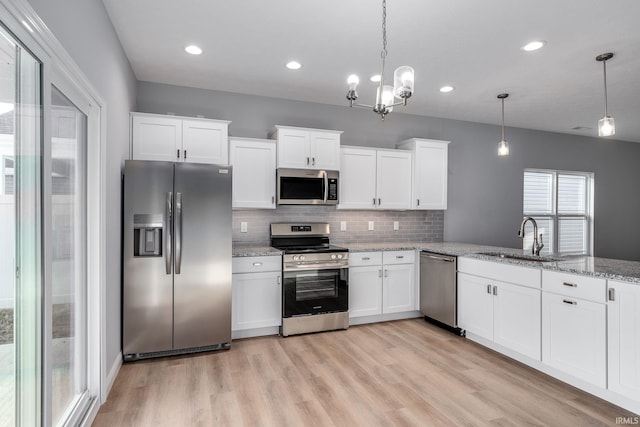 kitchen with light stone countertops, sink, pendant lighting, white cabinets, and appliances with stainless steel finishes